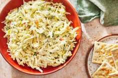 a red bowl filled with coleslaw next to crackers