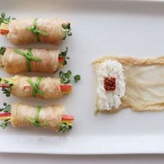 four sushi rolls on a white plate with rice and garnishes in them