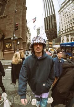 a man walking down the street wearing a hat and holding a skateboard in his hand