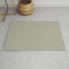 an empty room with a rug and basket on the floor next to it, in front of a white wall