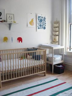 a baby's room with a crib, window and rug on the floor