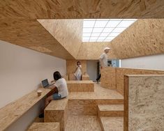 two people are sitting on wooden stairs in a room with plywood walls and flooring