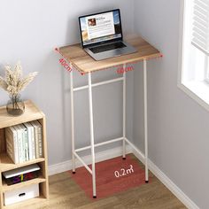 a laptop computer sitting on top of a wooden desk next to a book shelf and window