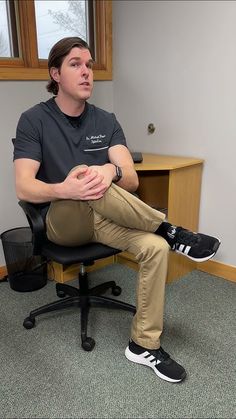 a man sitting in an office chair with his feet crossed and hands folded up on the desk