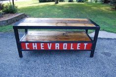 a table with the word chevrolet painted on it in front of some grass and trees