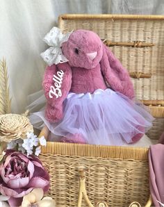 a pink teddy bear sitting in a wicker basket next to flowers and other items