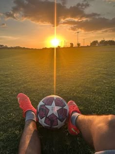 a soccer ball sitting on top of a field next to a person's legs