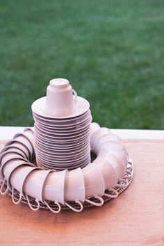 a stack of plates sitting on top of a wooden table next to a green field