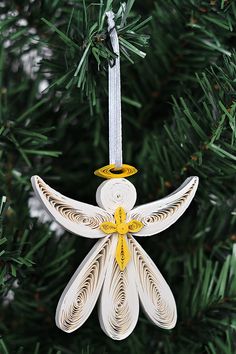 an ornament hanging from a christmas tree decorated with white and yellow designs on it