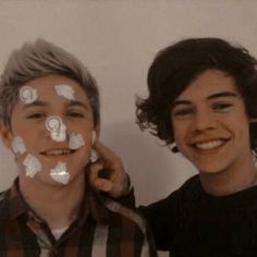 two young men standing next to each other with their faces covered in white stickers