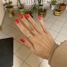 a woman's hand with red nail polish on it and two rings in the middle