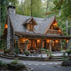 a small log cabin in the woods with lights on it's windows and porch