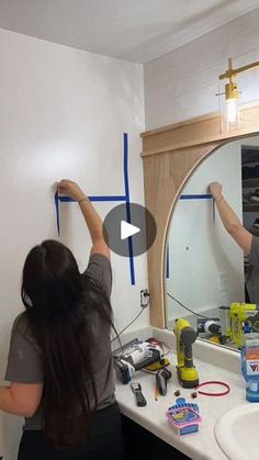 a man and woman standing in front of a bathroom mirror with tools on the counter