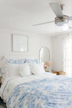 a bed with blue and white comforter in a bedroom next to a mirror on the wall