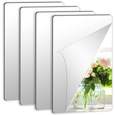 four white frames with flowers in them on a table