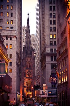 a city street filled with traffic and tall buildings at dusk, surrounded by tall skyscrapers