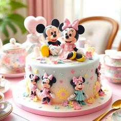 there is a cake decorated with mickey and minnie mouses on it's table