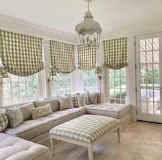 a living room filled with lots of furniture next to a window covered in green and white checkered curtains