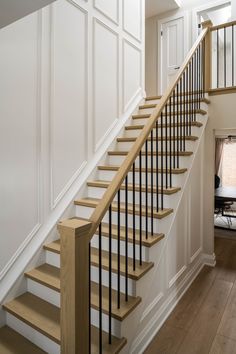 a wooden staircase with white walls and wood handrails in a home entryway