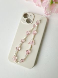 Add a touch of whimsy to your phone with our charming beaded phone strap. Crafted with delicate small pearls and accented with adorable pink butterfly and heart beads, this phone charm is the perfect blend of elegance and fun. Designed to be both stylish and functional, it can be used as a phone chain, keychain, or bracelet. This delightful accessory is ideal for adding a unique flair to your phone and makes a thoughtful gift for any occasion. Iphone Keychain Beads, Pink Phone Strap, Pink Phone Charm, Pearl Phone Charm, Beaded Phone Strap, Phone Keychain, Homemade Necklaces, Strap Phone, Butterfly Heart