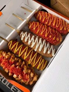 four hot dogs in a box with ketchup and mustard drizzled on them