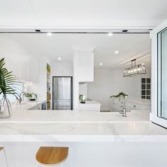 a white kitchen with marble counter tops and stools