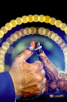 a close up of a person's hand holding a ring with lights in the background