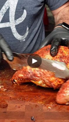 a man is cutting up some meat on a wooden table with a knife and black gloves