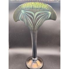 an art glass vase sitting on top of a metal table next to a light fixture