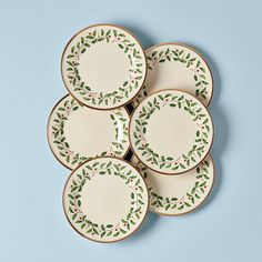 four plates with holly designs on them are arranged in the shape of wreaths and leaves