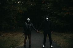 two people in masks holding hands on a path