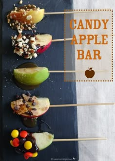 candy apple bar is displayed on a black slate platter with apples and candies