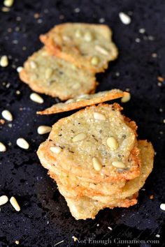 three cookies with nuts on top of them are sitting on a black surface next to some seeds