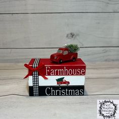 a red truck with a christmas tree on top of it sitting in front of a box