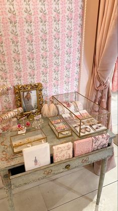 a table with many items on it in front of a pink and white wallpaper