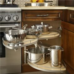 pots and pans are stored in the corner of this kitchen cabinet, which is open to reveal stainless steel appliances