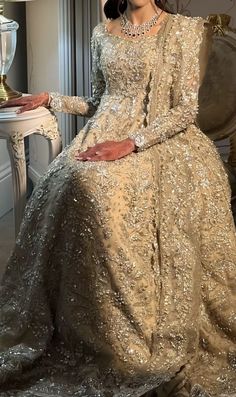 a woman sitting on top of a chair wearing a dress with gold sequins