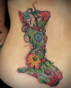 a woman's lower back tattoo with flowers and butterflies on her stomach, showing the upper half