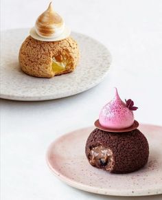 two desserts on plates one has a pink frosting and the other is chocolate