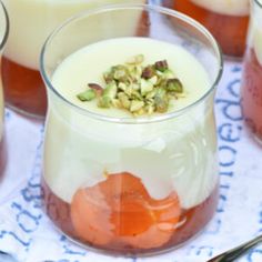 several glasses filled with different types of desserts on a table cloth next to spoons and utensils