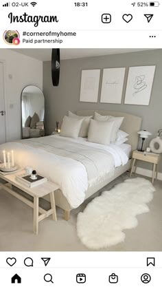 a bed with white sheets and pillows in a bedroom next to a table with candles on it