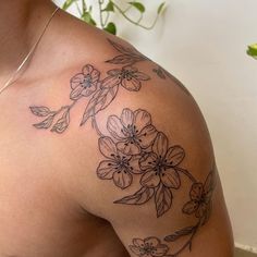 a close up of a person's shoulder and arm with flowers tattooed on it