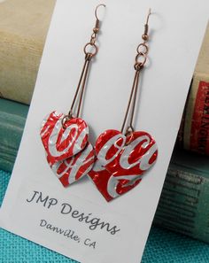 red and white heart shaped earrings with the word love spelled on them, hanging from gold earwires