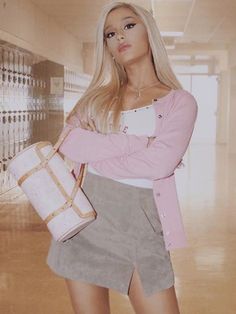 a woman standing in a hallway with her arms crossed and holding a white purse over her shoulder