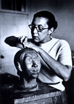 a black and white photo of a woman shaving a statue with a blow dryer