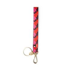 a pink and black keychain with a red flower design on the front, hanging from