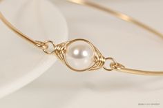 Wire Wrapped White Pearl Bangle Handmade by Jessica Luu Jewelry ~ Sophisticated ~ Versatile ~ Elegant ~ Perfect for everyday wear, this white pearl bangle adds a touch of casual elegance to every occasion - available in 2 metal choices. MATCHING ITEMS https://www.etsy.com/shop/JessicaLuuJewelry?search_query=white+pearl+wp MATERIALS: ~ 10mm white Swarovski pearl ~ 14K gold filled wire HOW IT'S MADE: A large Swarovski pearl is wire wrapped in a herringbone style then attached to a bangle bracelet Real Pearl Bracelet, Pearl Bangle Bracelet, Pearl Cuff Bracelet, Bijoux Fil Aluminium, Swarovski Crystal Rings, Solid Gold Bracelet, Rose Gold Bangle, Pearl Bangle, The Bangles