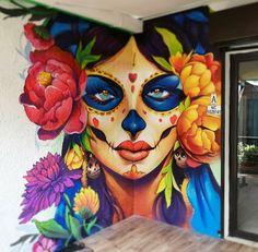 a colorful mural on the side of a building shows a woman's face and flowers