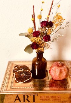 a vase filled with flowers sitting on top of a wooden table next to an orange