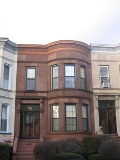 a row of townhouses with trees and bushes in front